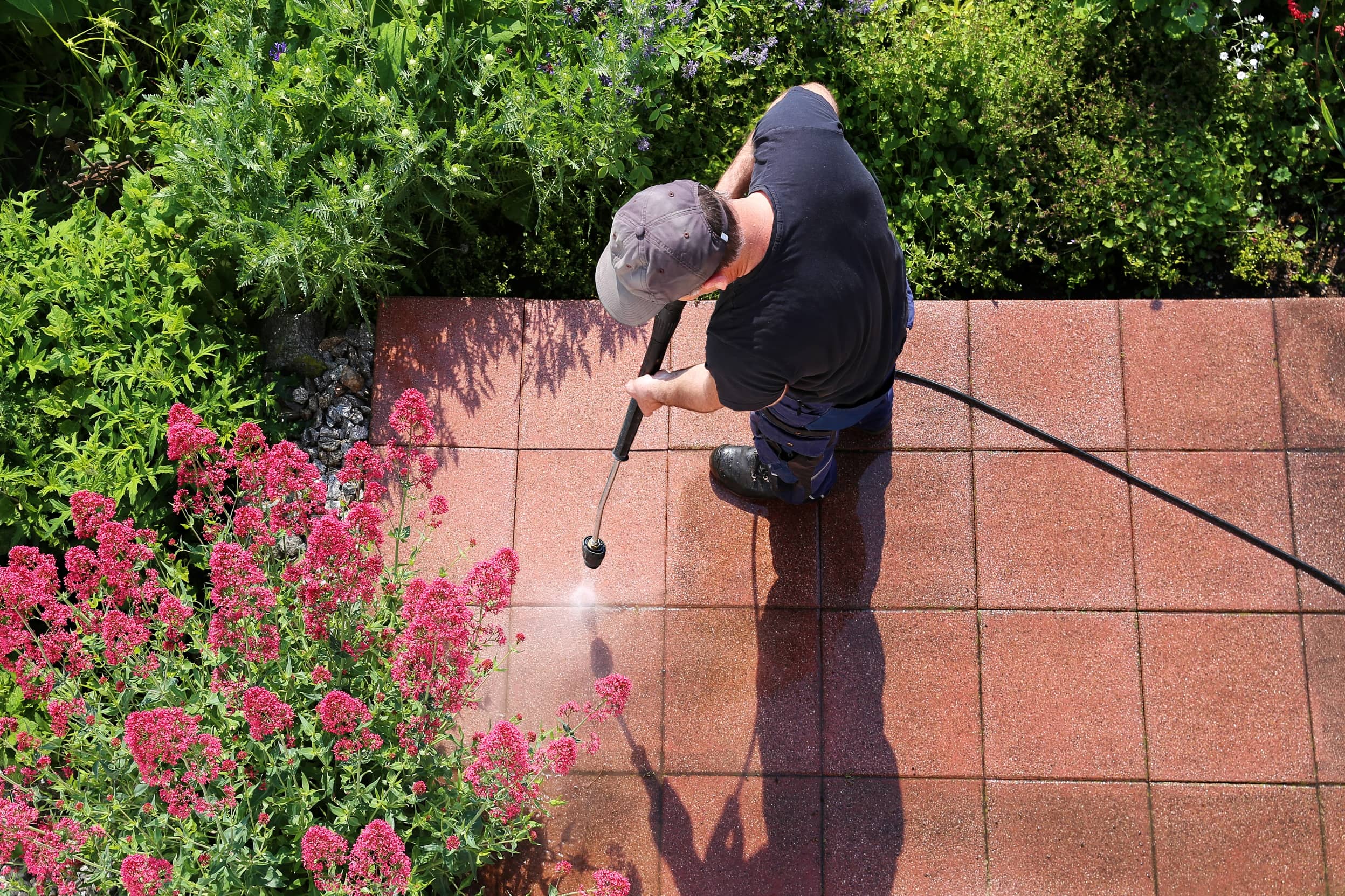 Hombre utilizando un limpiador a presión en una terraza impermeabilizada