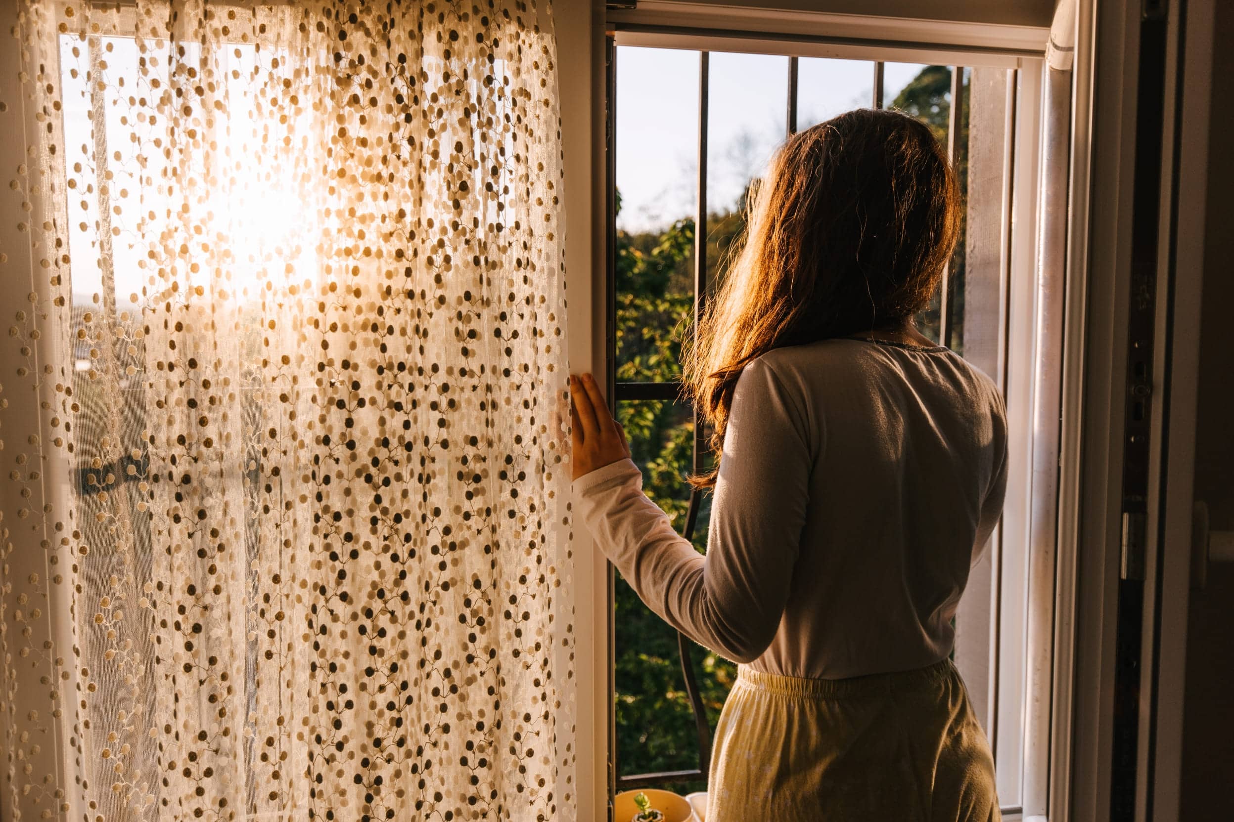 Mujer mirando a través de una ventana con rejas