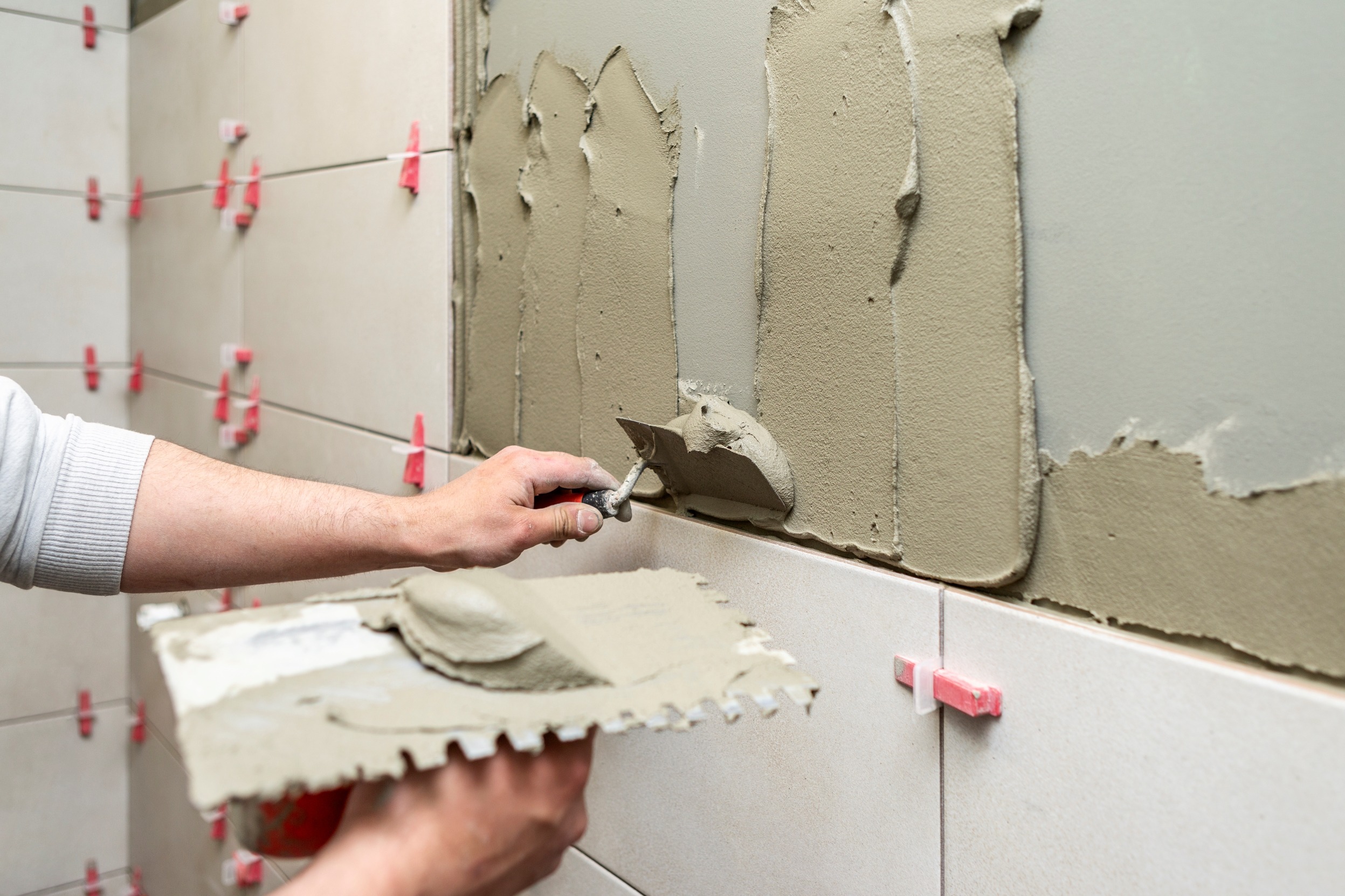 mano cogiendo cemento de una paleta y poniéndolo sobre una pared