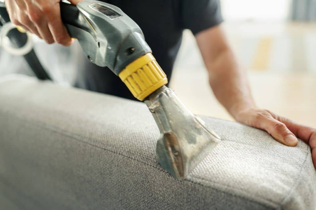 Profesional de limpieza realizando una limpieza en profundidad en una sala de estar