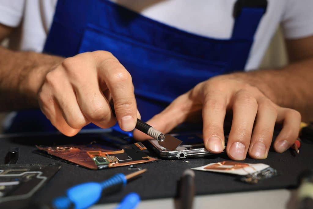 Técnico reparando una consola de videojuegos con herramientas especializadas
