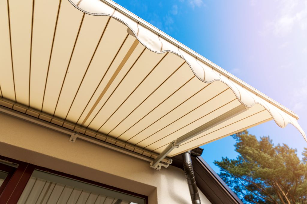 Toldo retráctil moderno instalado en una terraza, ofreciendo sombra y elegancia a un espacio exterior acogedor. 