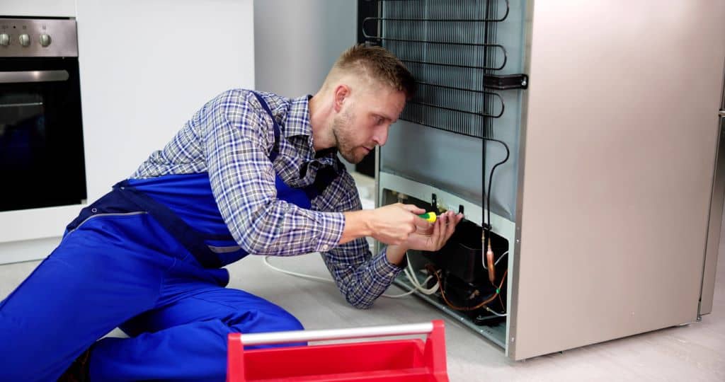 Técnico realizando el mantenimiento preventivo de un electrodoméstico en el hogar.
