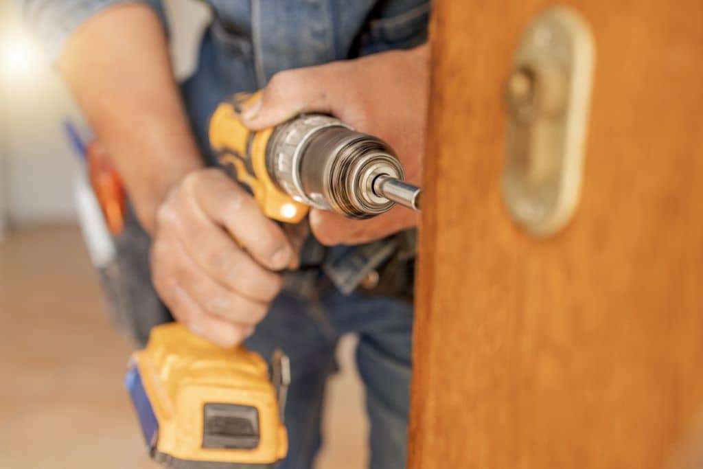 Cerrajero profesional abriendo una puerta de madera con herramientas especializadas. 